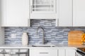 A kitchen faucet detal with white cabinets and a blue glass tile backsplash. Royalty Free Stock Photo