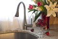 Kitchen faucet, strawberries and fresh flowers on a counter. Royalty Free Stock Photo