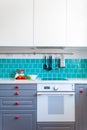 Kitchen features dark gray flat front cabinets paired with white quartz countertops and a glossy blue care tile. Royalty Free Stock Photo