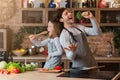 Kitchen Fun. Cheerful dad and his little daughter singing while cooking together