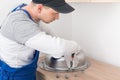 Kitchen furniture assembly worker inserts fixtures into the sink to secure it, side view