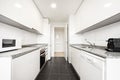 Kitchen with gloss white cabinets on both walls, gray granite