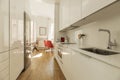 Kitchen with gloss white wood cabinetry, white stone countertops, white built-in appliances and chestnut hardwood floors and Royalty Free Stock Photo