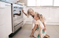 Kitchen, happy and grandmother with a kid by the oven watching the cake, cookies or pie bake. Happiness, smile and Royalty Free Stock Photo