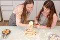 In the kitchen at home, a playful mother and daughter yell while making pizza dough