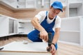 Kitchen installation. Worker assembling furniture