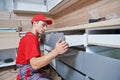 Kitchen installation. Worker assembling furniture