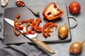 Kitchen knife, chopped red pepper, and half pepper on cutting board. Garlic and spoon with tomato sauce Royalty Free Stock Photo