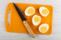 Knife, halves of peeled eggs on cutting board on wooden table. Top view Royalty Free Stock Photo