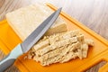 Kitchen knife on pieces of cutted peanut halva on cutting board on table