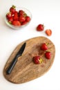 Kitchen knife and plate with fresh strawberries lying on wood board in the kitchen