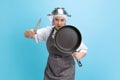 Kitchen knight. Comic portrait of pretty man, cook, female chef in white uniform having fun isolated on blue background Royalty Free Stock Photo