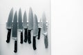 Kitchen knives set on a magnet on a light wall for background. T Royalty Free Stock Photo