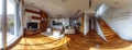 a kitchen and living room with wooden accents, featuring a panoramic view that includes stairs ascending to the second Royalty Free Stock Photo