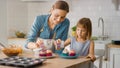 In the Kitchen: Mother and Cute Little Daughter Sprinkling Funfetti on Creamy Cupcakes Frosting. F Royalty Free Stock Photo