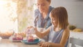 In the Kitchen: Mother and Cute Little Daughter Sprinkling Funfetti on Creamy Cupcakes Frosting. T Royalty Free Stock Photo