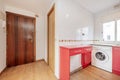 Kitchen with red wooden cabinets with white countertop, white tiles and sapele wood access door Royalty Free Stock Photo