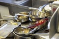 Kitchen in restaurant, sink filled with dirty metal dishes