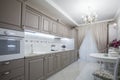 Kitchen room interior with white marble floor, countertops with built in cooker and comfortable wooden cupboards