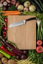 Kitchen Santoku Knife on Wood Cutting Board with Fresh Vegetables