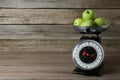 Kitchen scale with green apples on wooden table. Space for text Royalty Free Stock Photo