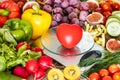 Kitchen scale with a red heart surrounded by fruits and vegetables. Concept of healthy eating and diet Royalty Free Stock Photo