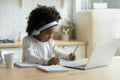 African schoolgirl in headphones using laptop do homework at home Royalty Free Stock Photo