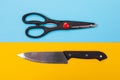 Scissors and knife isolated on yellow-blue background Royalty Free Stock Photo