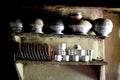 Kitchen shelf with steel and Aluminium pots and pans and plates and Ceramic cups in an Indian Kashmiri Kitchen with mud wall