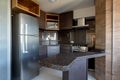 Silver fridge, stove and microwave. Central countertop. Dark environment with black granite furniture and dark wood