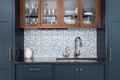 A kitchen sink surrounded by blue cabinets and a mosaic tile backsplash. Royalty Free Stock Photo