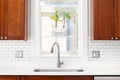 A kitchen sink detail with wood cabinets and subway tile backsplash. Royalty Free Stock Photo