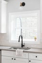 A kitchen sink detail with a hexagon backsplash and white cabinets. Royalty Free Stock Photo