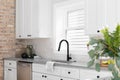 A kitchen sink detail with a hexagon backsplash and white cabinets. Royalty Free Stock Photo