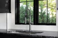 A kitchen sink detail shot in a black kitchen with a white backsplash. Royalty Free Stock Photo