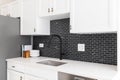 Kitchen sink detail with white cabinets and a black tile backsplash. Royalty Free Stock Photo