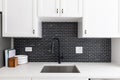 Kitchen sink detail with white cabinets and a black tile backsplash. Royalty Free Stock Photo