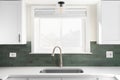 A kitchen sink detail in a white kitchen with green subway tile backsplash. Royalty Free Stock Photo