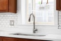 A kitchen sink detail with wood cabinets and subway tile backsplash. Royalty Free Stock Photo