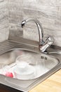 Kitchen sink full of foam, tableware and pink cleaning sponge Royalty Free Stock Photo