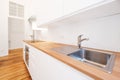 Kitchen sink and water tap in new white kitchenette with wooden worktop