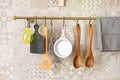 Kitchen spatulas hand on railing on a tiled wall with geometric pattern in kitchen in Scandinavian style.