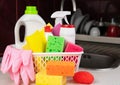 Kitchen sponges, various detergents, cleaners products and rubber gloves in the basket on the table at the kitchen. Cleaning