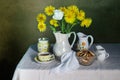 Kitchen still life with bagels, tea in a cup in a jug and flowers on the table. Royalty Free Stock Photo