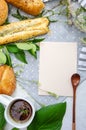 Kitchen table with blank card, wooden spoon, cup of tea and season herbs on cotton tablecloth. Blank for your design app over