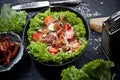 Kitchen table with green salad, bowls with tomatoes, parmesan cheese and grater, fork and knife, flatlay Royalty Free Stock Photo