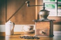 Old coffee grinder in a rustic farmhouse with coffee beans, milk jug and coffee cup Royalty Free Stock Photo