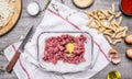 Kitchen table preparation of raw minced meat chopped onion seasoning eggs tomato sauce penne kitchen knife a white napkin on w Royalty Free Stock Photo