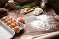 On the kitchen table, a ready-made dough, scattered flour and a tray with eggs. Royalty Free Stock Photo