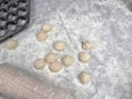 on the kitchen table are several dumplings with meat, a wooden rolling pin and a form for sculpting dumplings Royalty Free Stock Photo